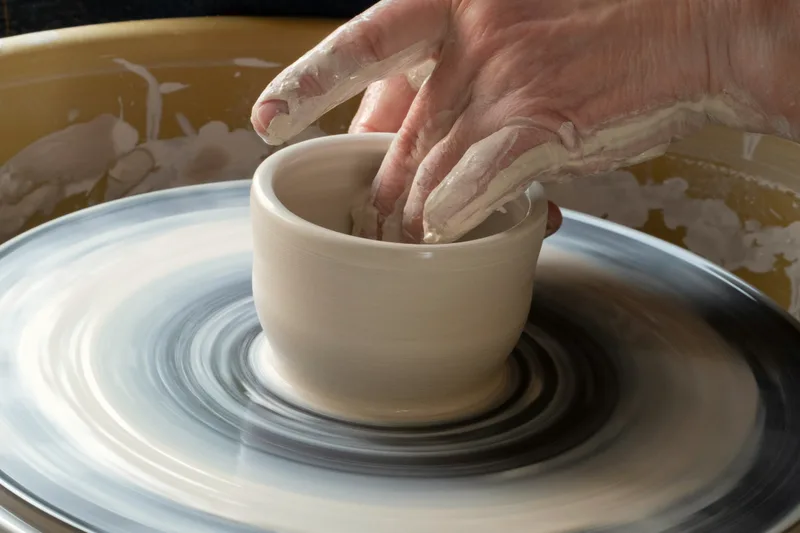 A potter shaping a bowl on the wheel